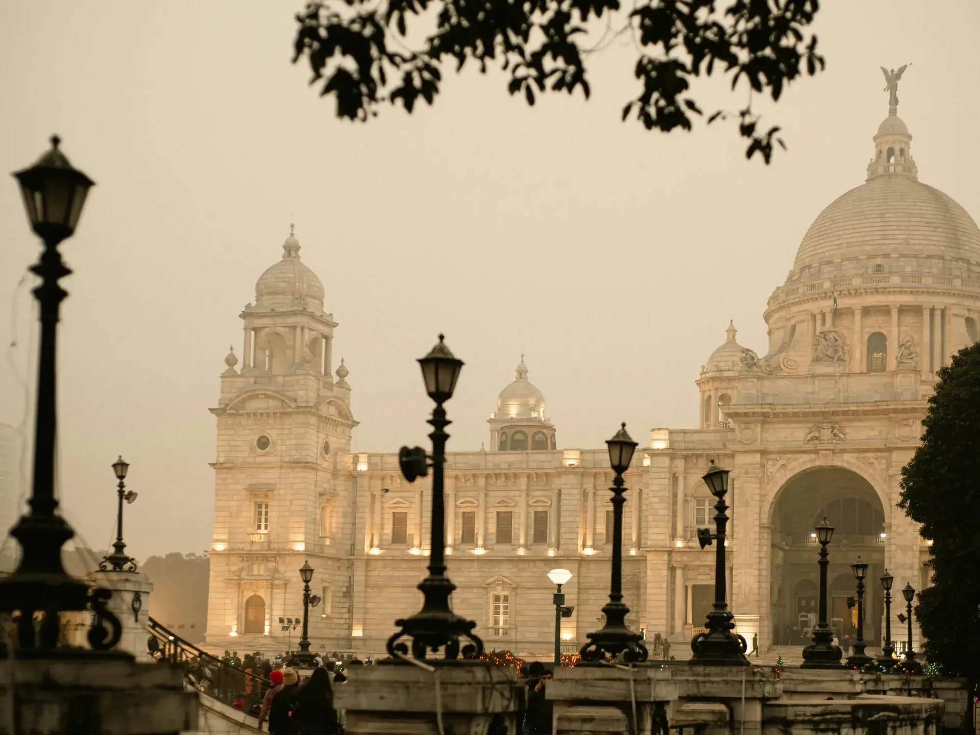 Victoria Memorial in Kolkata lit up at dusk behind a row of old street lamps